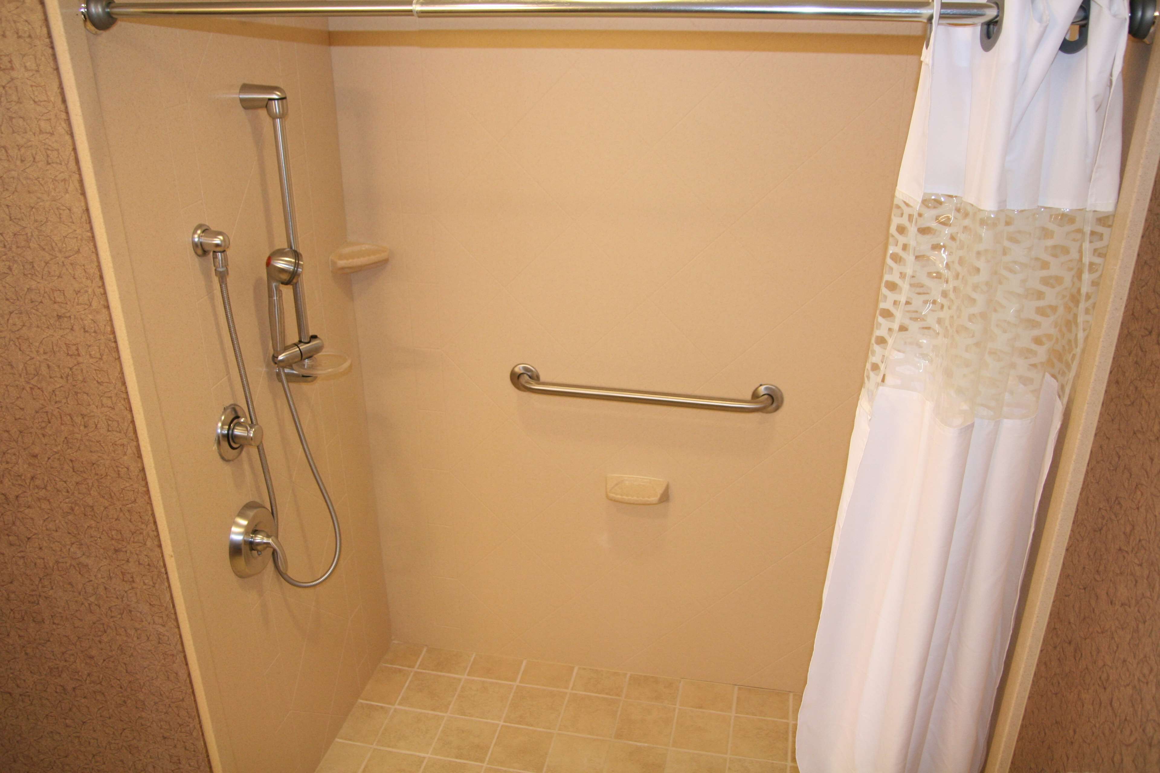 A shower with a grab bar, a towel rack, and a shower curtain.