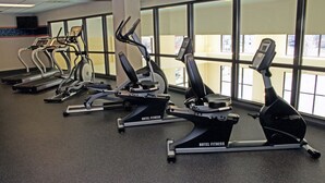 A row of stationary bikes labeled "Hotel Fitness" in a gym with large windows. - Hampton Inn & Suites Chesapeake-Battlefield Blvd. (Chesapeake)