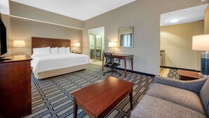 A hotel room with a bed, a desk, a chair, a sofa, and a coffee table.