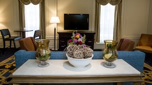 A hotel room with a television, two vases with decorative items, a sofa, and a small table.