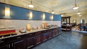 A hotel kitchen with a long counter, equipped with various appliances and food items.