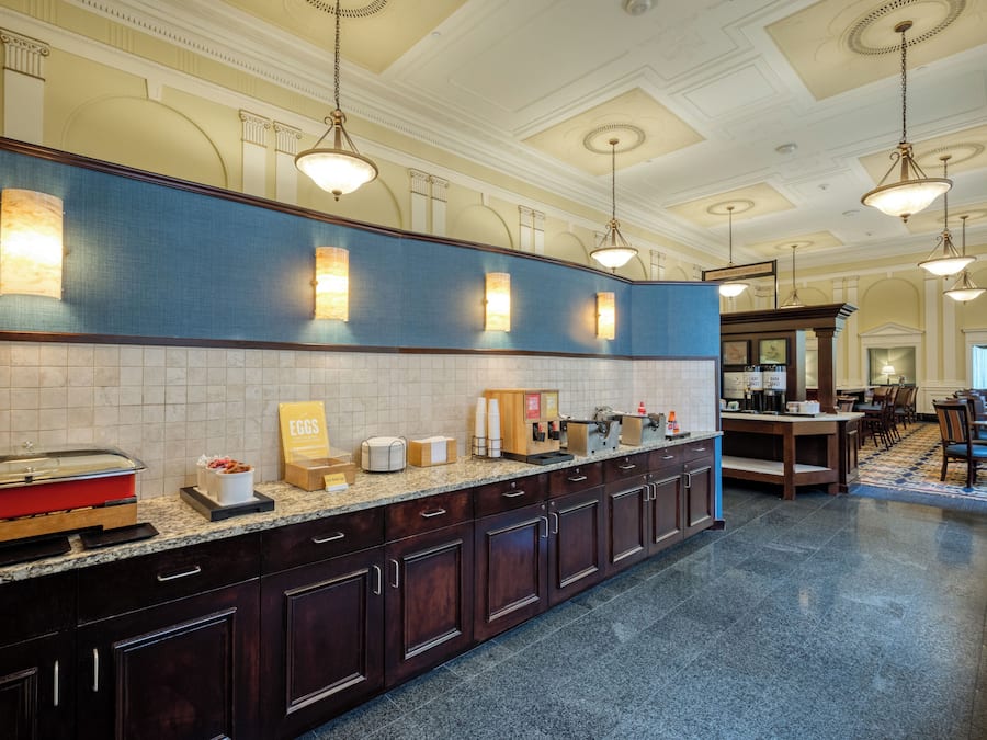 A hotel kitchen with a long counter, equipped with various appliances and food items.