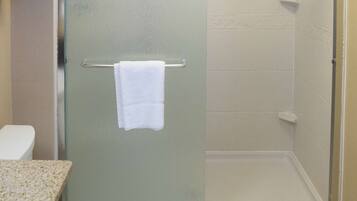 A bathroom with a glass-enclosed shower, a toilet, and a towel rack with towels.