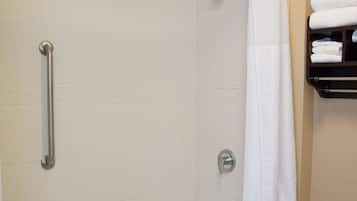 Un baño moderno con cabina de ducha, barra de apoyo y repisa con toallas.