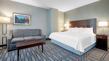 Une chambre d’hôtel avec un grand lit, un canapé, une table basse et un tableau encadré au mur.
