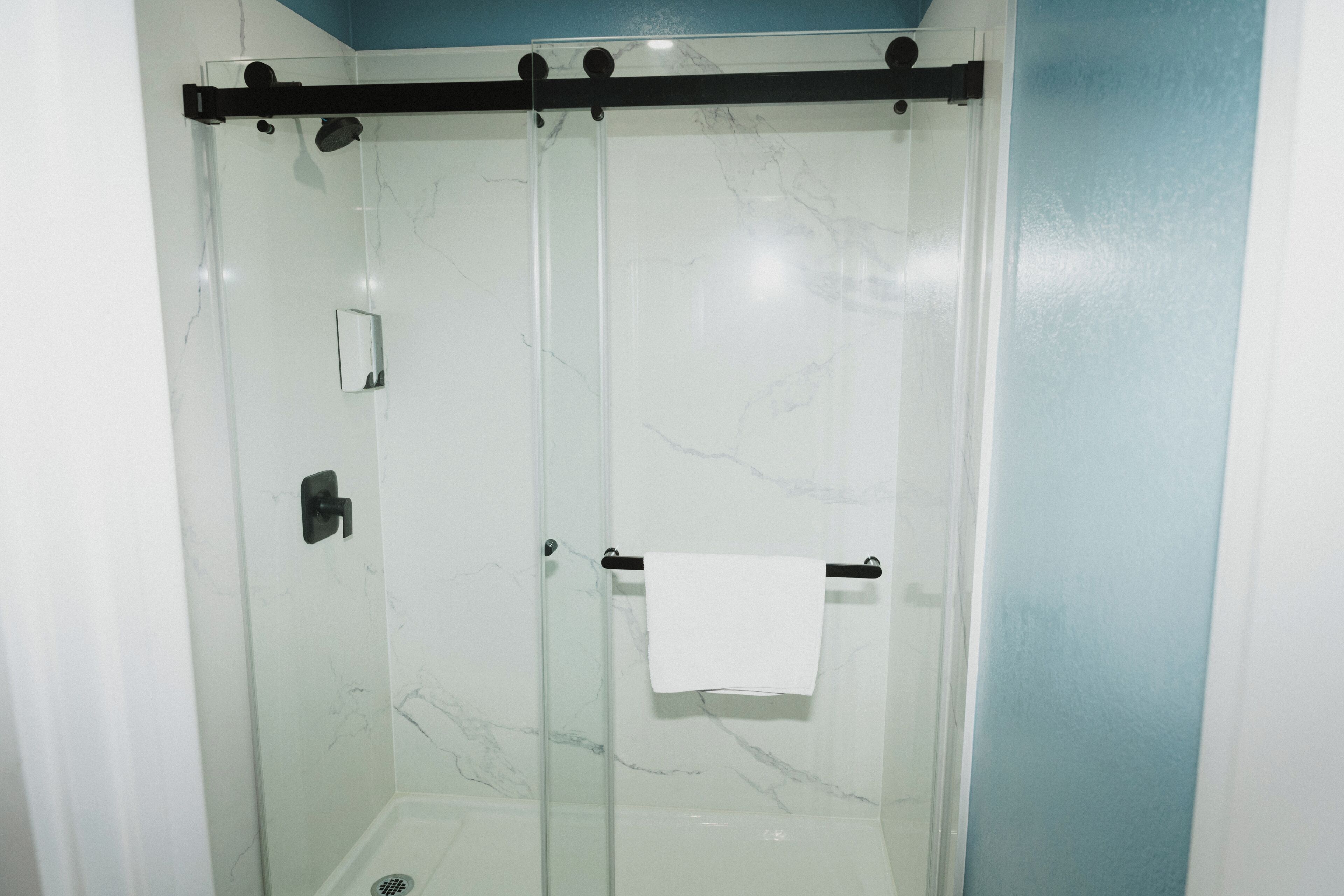 A glass-enclosed shower with a towel rack and a small mirror.