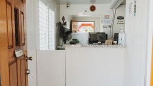 A narrow kitchen with white cabinets, a wooden door, and a countertop with a fan and a small plant. - Hotel Paso Robles Wine Country (Paso Robles)