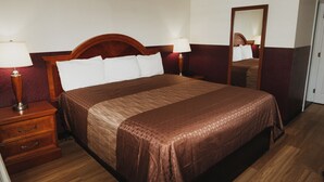 A neatly made bed with a wooden headboard, two bedside tables with lamps, and a mirror on the wall. - Hotel Paso Robles Wine Country (Paso Robles)