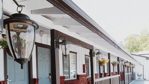 A covered outdoor area with a bench, a row of doors, and hanging flower baskets. - Hotel Paso Robles Wine Country (Paso Robles)