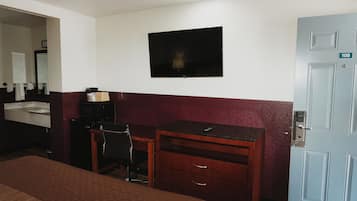 Ein Hotelzimmer mit einem Bett, einem Schreibtisch mit Stuhl, einem Fernseher, einem Badezimmer mit Waschbecken und einer Tür mit der Nummer 108.