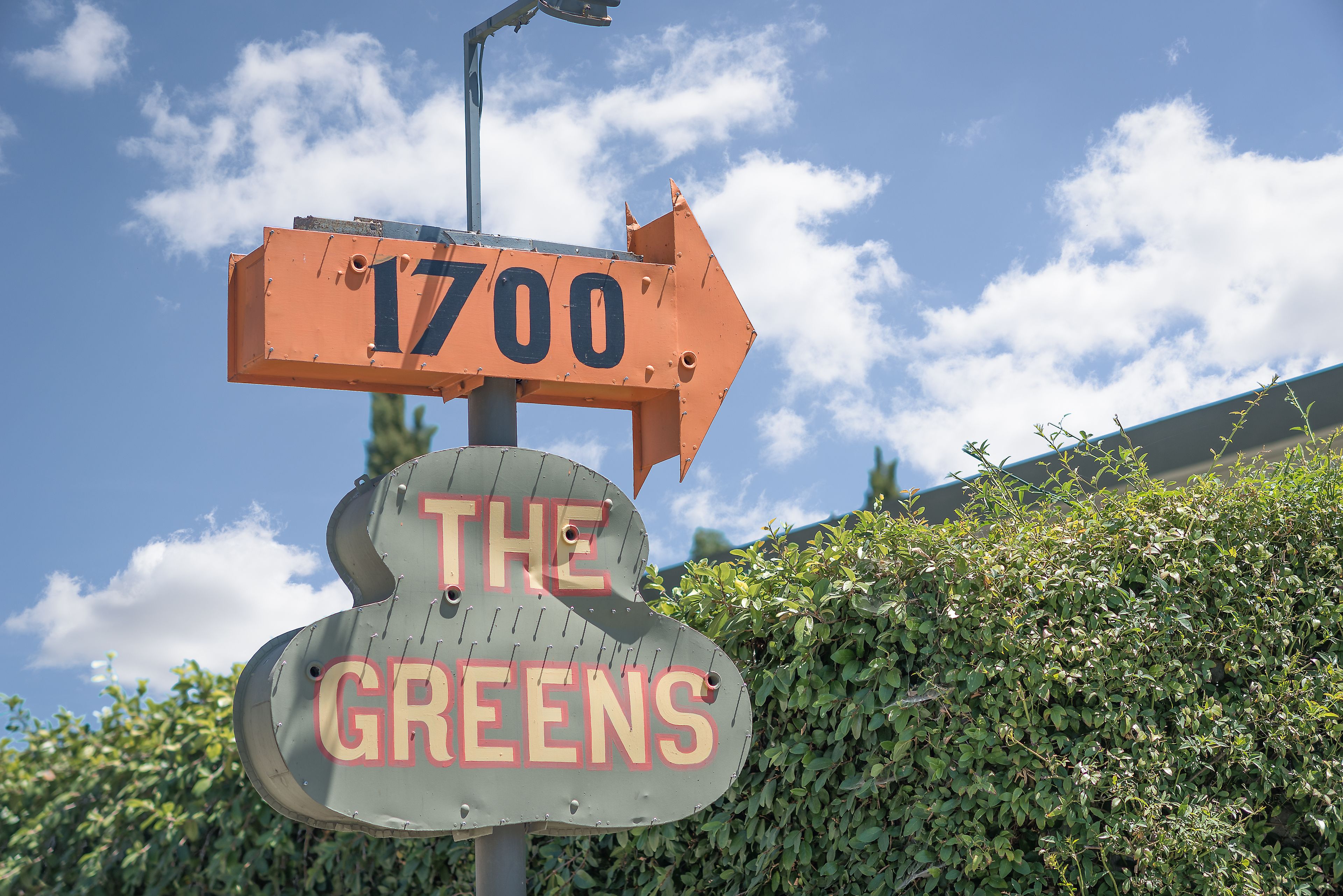 Un panneau de signalisation indiquant la direction, avec le numéro 1700 et le texte « THE GREENS », pointant vers la droite.