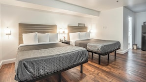 Une chambre d’hôtel avec deux lits, une tête de lit en bois, des lampes de chevet et un réfrigérateur.