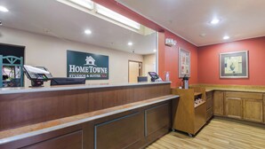A reception desk with a sign for Home Towne Studios & Suites. - HomeTowne Studios & Suites by Red Roof Bentonville (Bentonville)