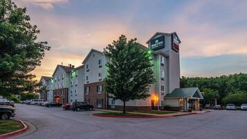 A hotel with multiple buildings, a parking lot, and a green-lit entrance.
