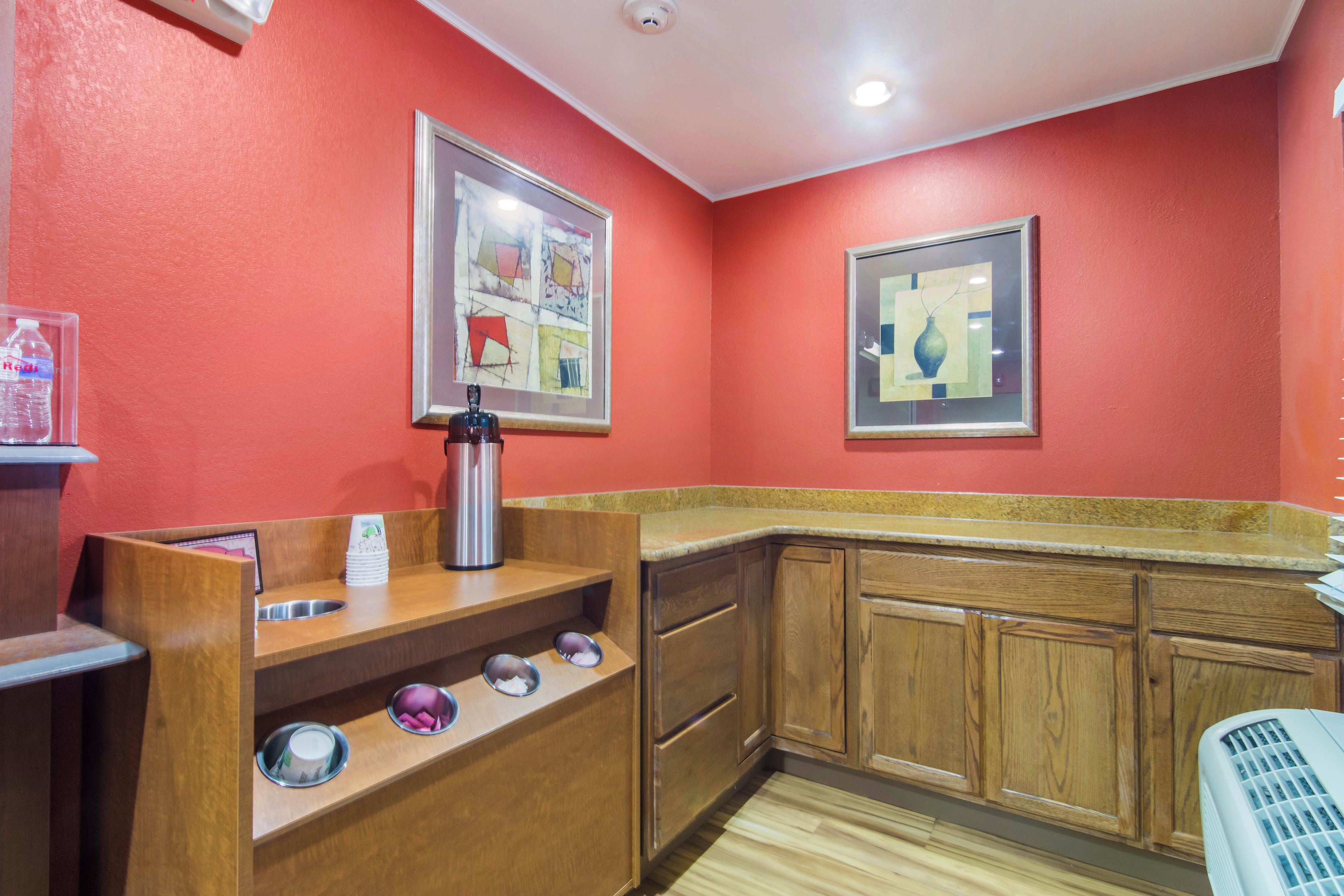 A kitchen with wooden cabinets, a stainless steel kettle, and a water dispenser on a counter.