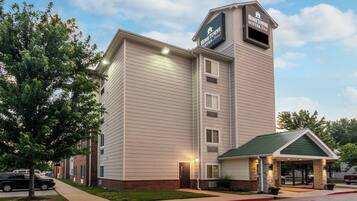 A hotel with a prominent sign, a covered entrance, and a parking area.