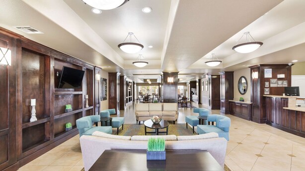 A spacious lobby with a central seating area, a reception desk, and a television mounted on the wall.