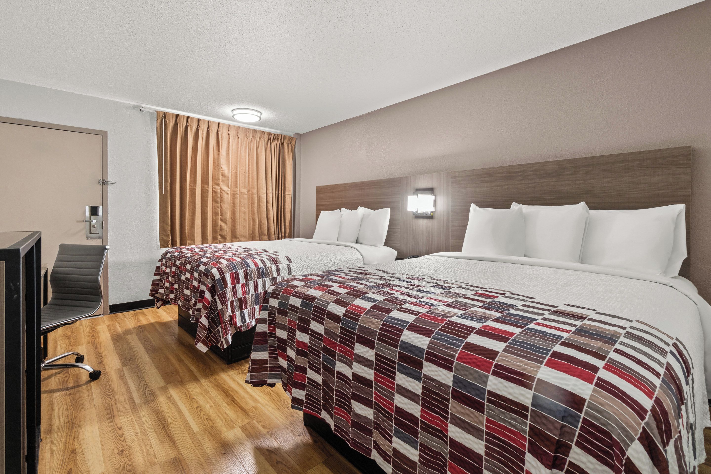 Habitació d'hotel amb dos llits, una taula i una cadira.