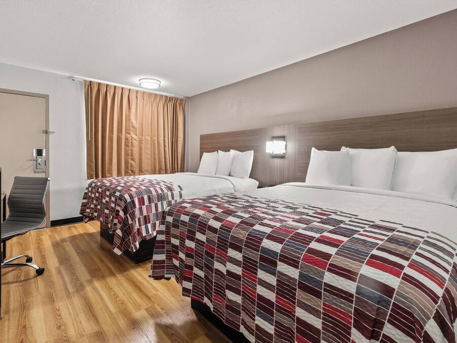 Ein Hotelzimmer mit zwei Betten, einem Schreibtisch und einem Stuhl.