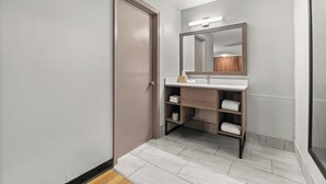A modern bathroom with a wooden vanity, a large mirror, and a towel rack.
