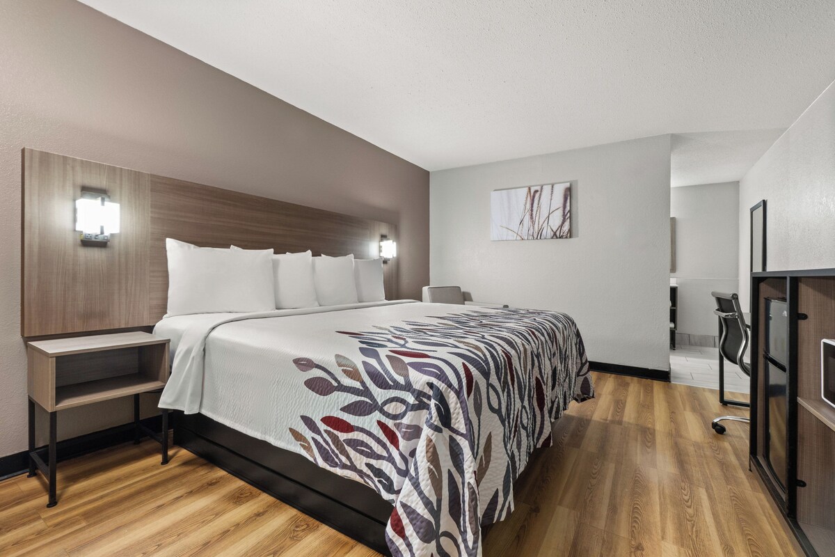 A modern hotel room with a large bed, bedside tables, a desk, and a chair.