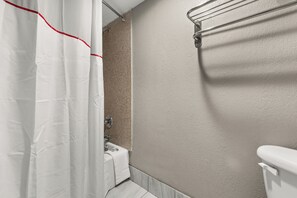A bathroom with a white bathtub, a shower curtain, and a toilet. - Red Roof Inn Memphis - Graceland/ Airport (Memphis)