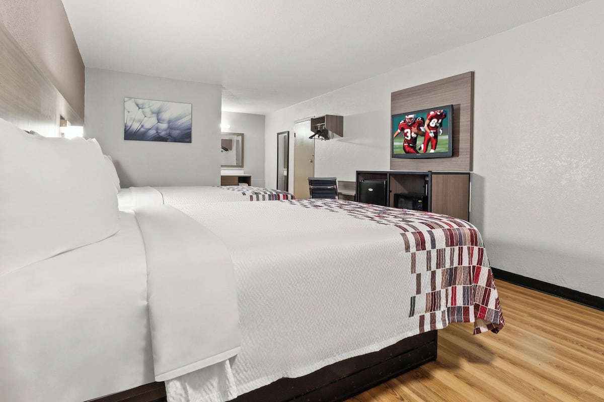 Ein modernes Hotelzimmer mit einem großen Bett, einem Schreibtisch, einem Fernseher und einem Bild an der Wand.