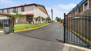 A gated street with a building on the left and a fence on the right. - Red Roof Inn Memphis - Graceland/ Airport (Memphis)