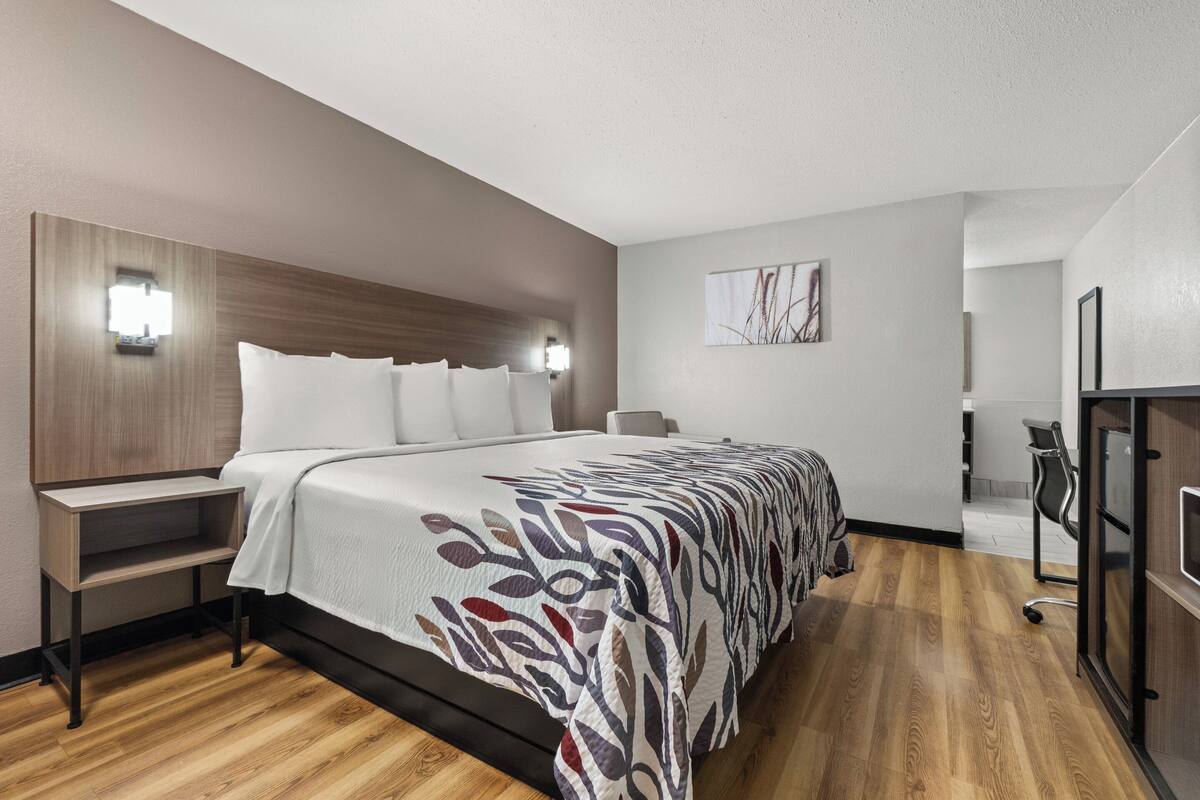 Ein modernes Hotelzimmer mit einem großen Bett, Nachttischen, einem Schreibtisch und einem Sessel.