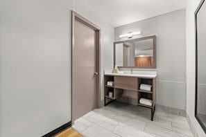 A modern bathroom with a wooden vanity, a large mirror, and a towel rack.