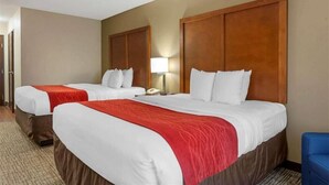 A hotel room with two beds, each with a wooden headboard, white bedding, and a red accent. - Springplace Inn & Suites (Marion)
