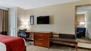 A hotel room with a bed, desk, chair, and a television.