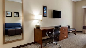 A hotel room with a large mirror, a desk with a chair, a television, and a sofa. - Springplace Inn & Suites (Marion)