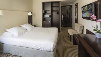 Une chambre d’hôtel avec un grand lit, un bureau, une chaise, une télévision et une armoire.