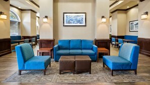 A lobby with a blue sofa set, two ottomans, and wall-mounted lights. - Comfort Suites Frisco (Frisco)