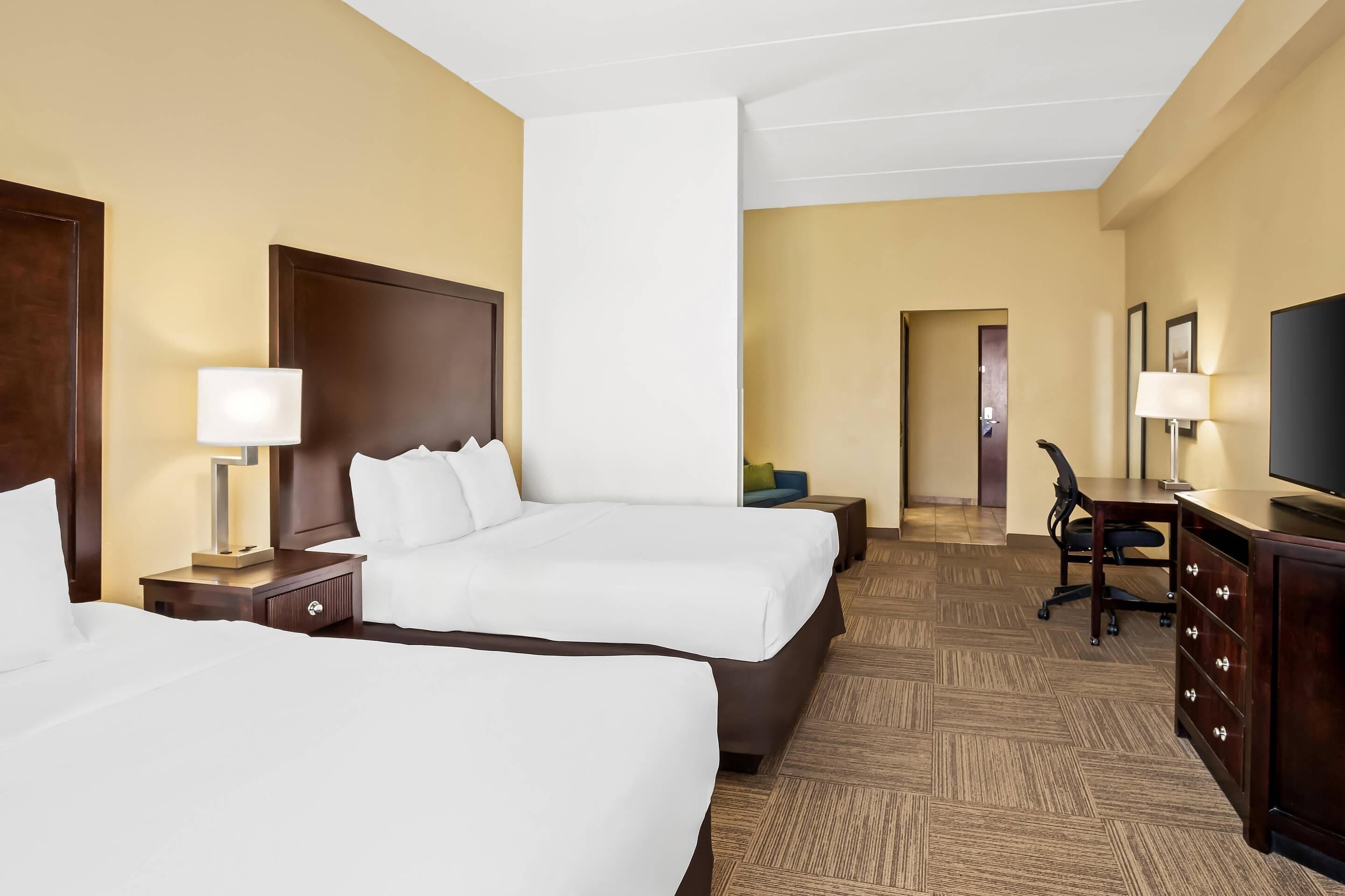 Ein Hotelzimmer mit zwei Betten, einem Schreibtisch, einem Stuhl und einem Fernseher.