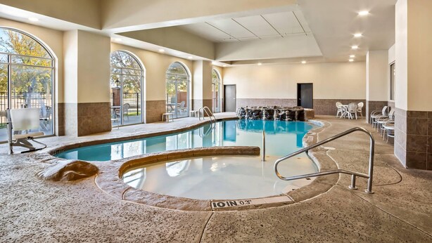 An indoor swimming pool with a spa area, seating, and a view of the outdoors. - Comfort Suites Frisco (Frisco)