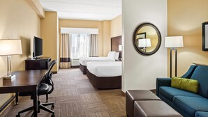 A hotel room with a desk, two beds, a sofa, a TV, and a mirror. - Comfort Suites Frisco (Frisco)