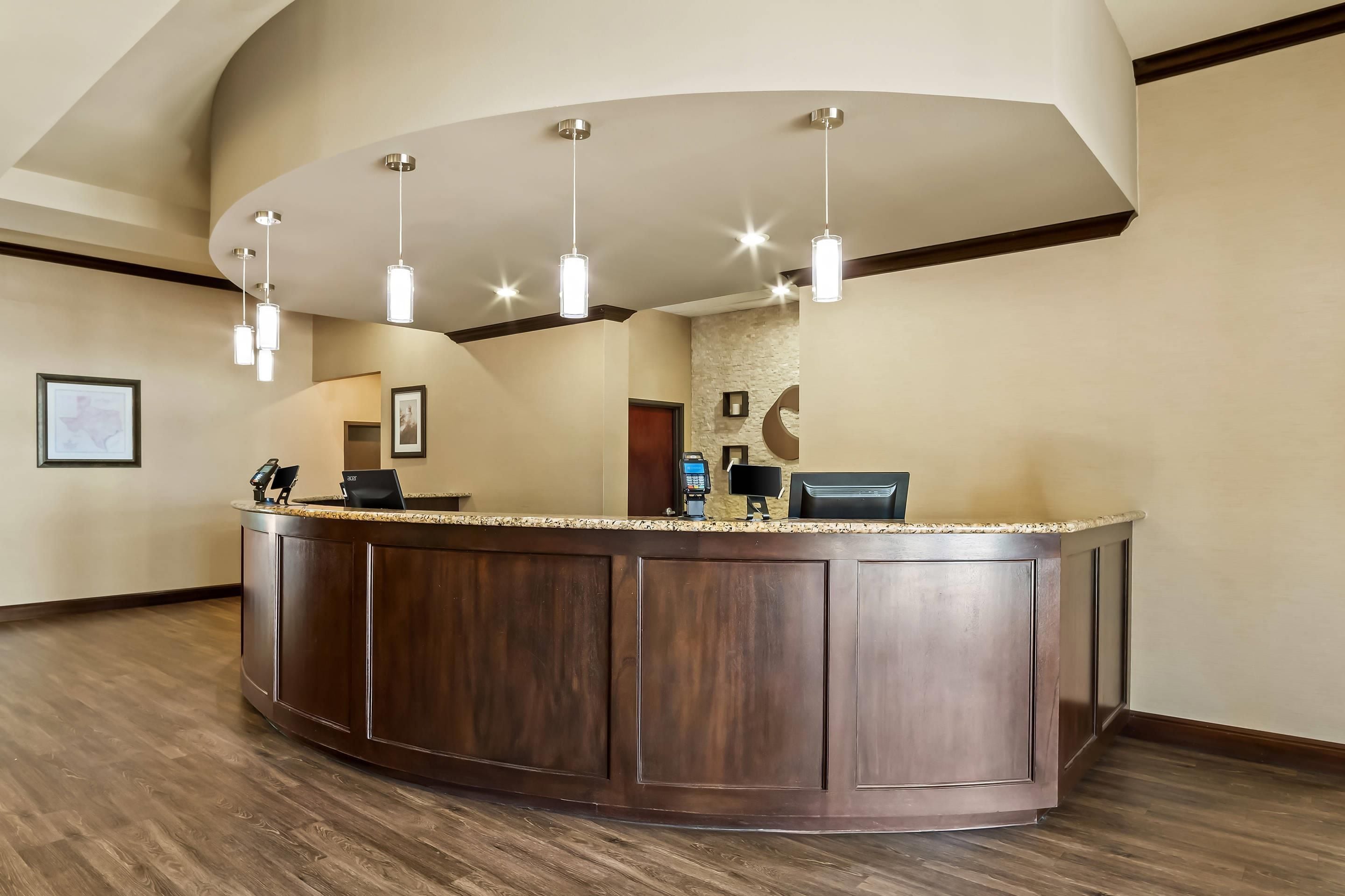 A reception area with a curved wooden counter, pendant lighting, framed pictures on the walls, and a stone accent wall.