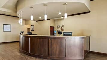 A reception area with a curved wooden counter, pendant lighting, framed pictures on the walls, and a stone accent wall.