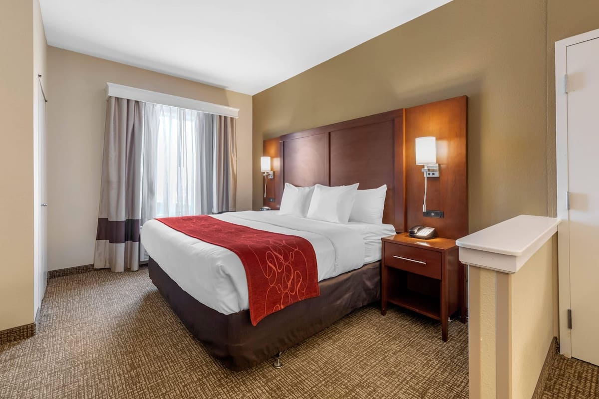 Ein Hotelzimmer mit einem großen Bett, Nachttischlampen, einem Nachttisch und einem Schreibtisch mit Telefon.