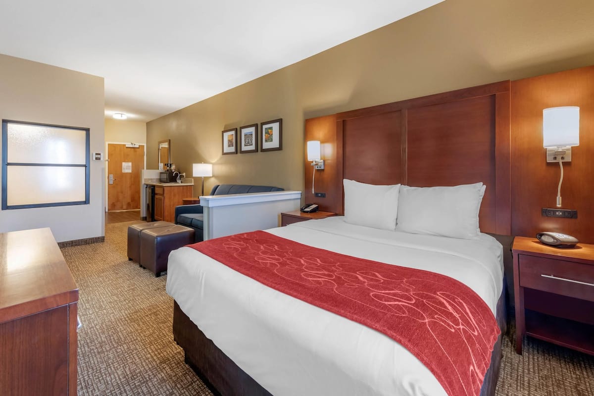 Ein Hotelzimmer mit einem großen Bett, einem Schreibtisch, einem Stuhl, einem Schminktisch und einem Badezimmer.