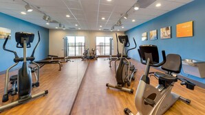 Une salle de sport équipée de matériel d’exercice, dotée de grandes fenêtres et agrémentée de décorations murales inspirantes.