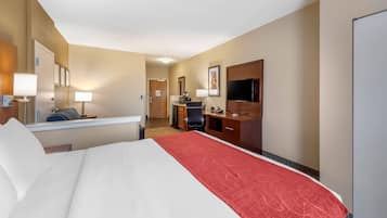 A hotel room with a bed, desk, chair, TV, and a door.