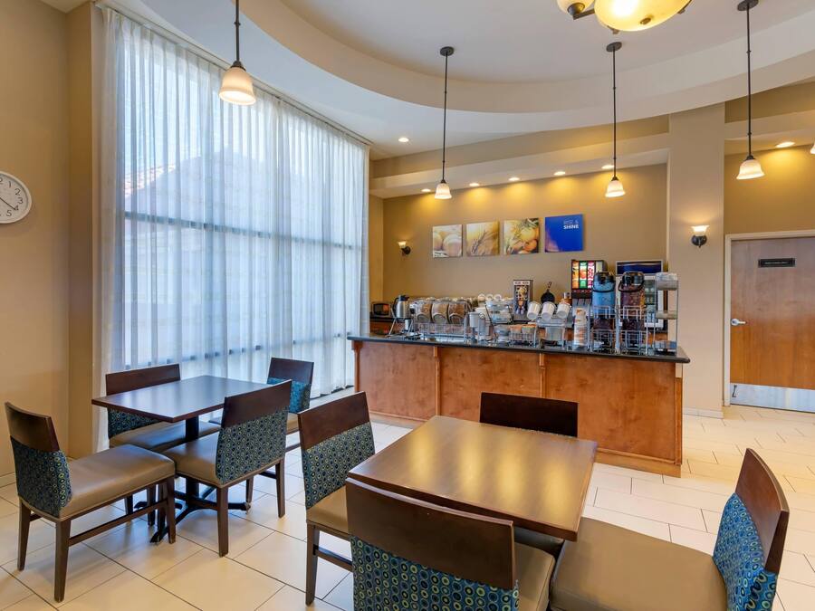 A hotel dining area with a long table, chairs, a bar, and a clock on the wall.