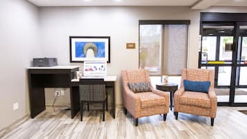 A reception area with a desk, two patterned armchairs, a framed picture, and a window with a view.