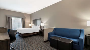 Ein Hotelzimmer mit einem Bett, einem blauen Sofa, einem Schreibtisch und einem Sessel.