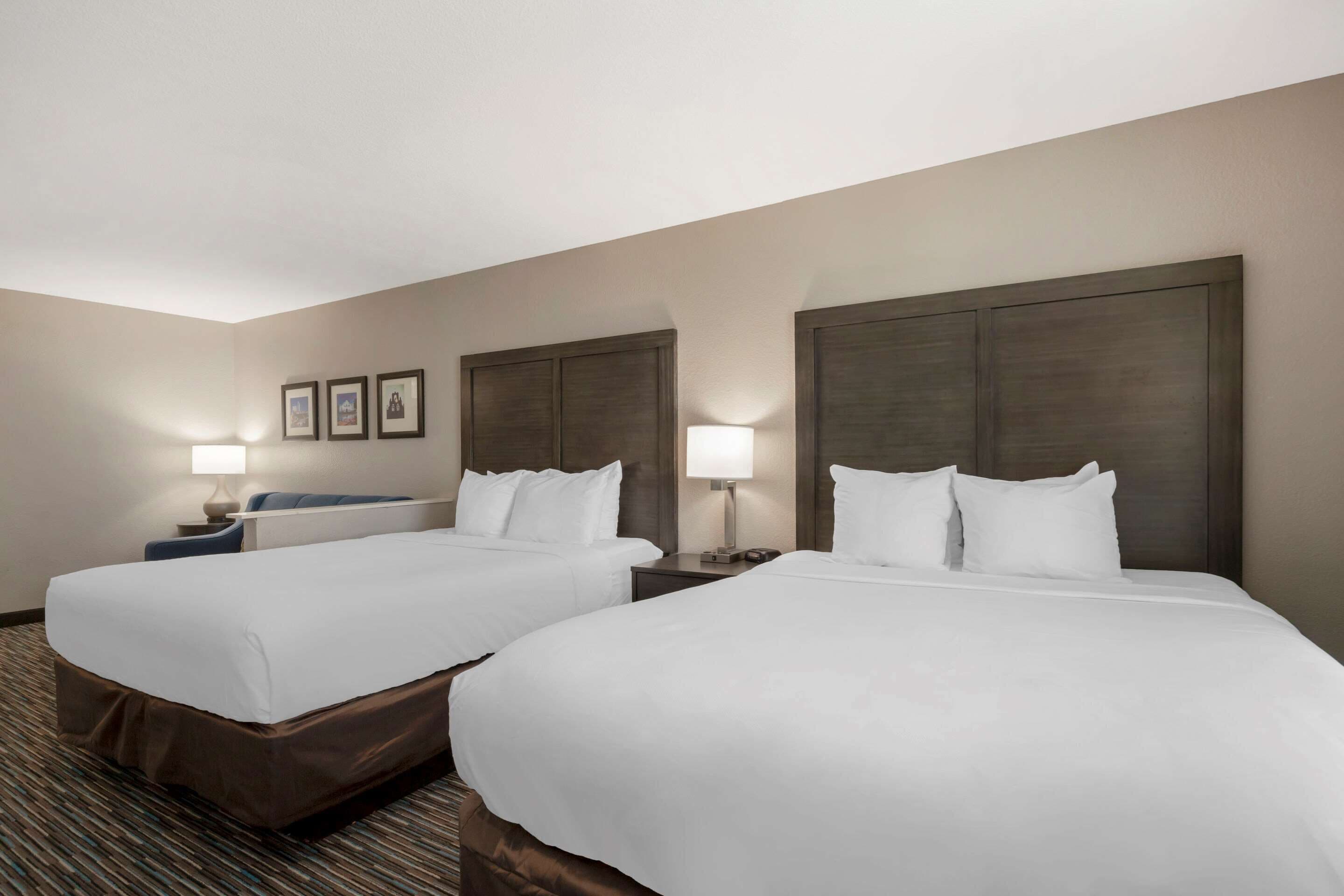 A hotel room with two beds, a desk, and a chair.
