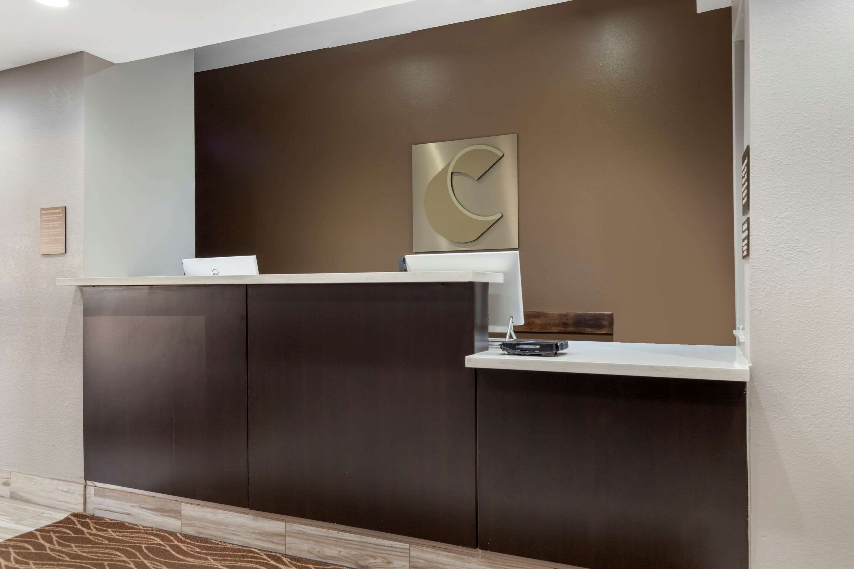 A reception desk with a dark wood finish, a white counter, and a large abstract wall art piece.
