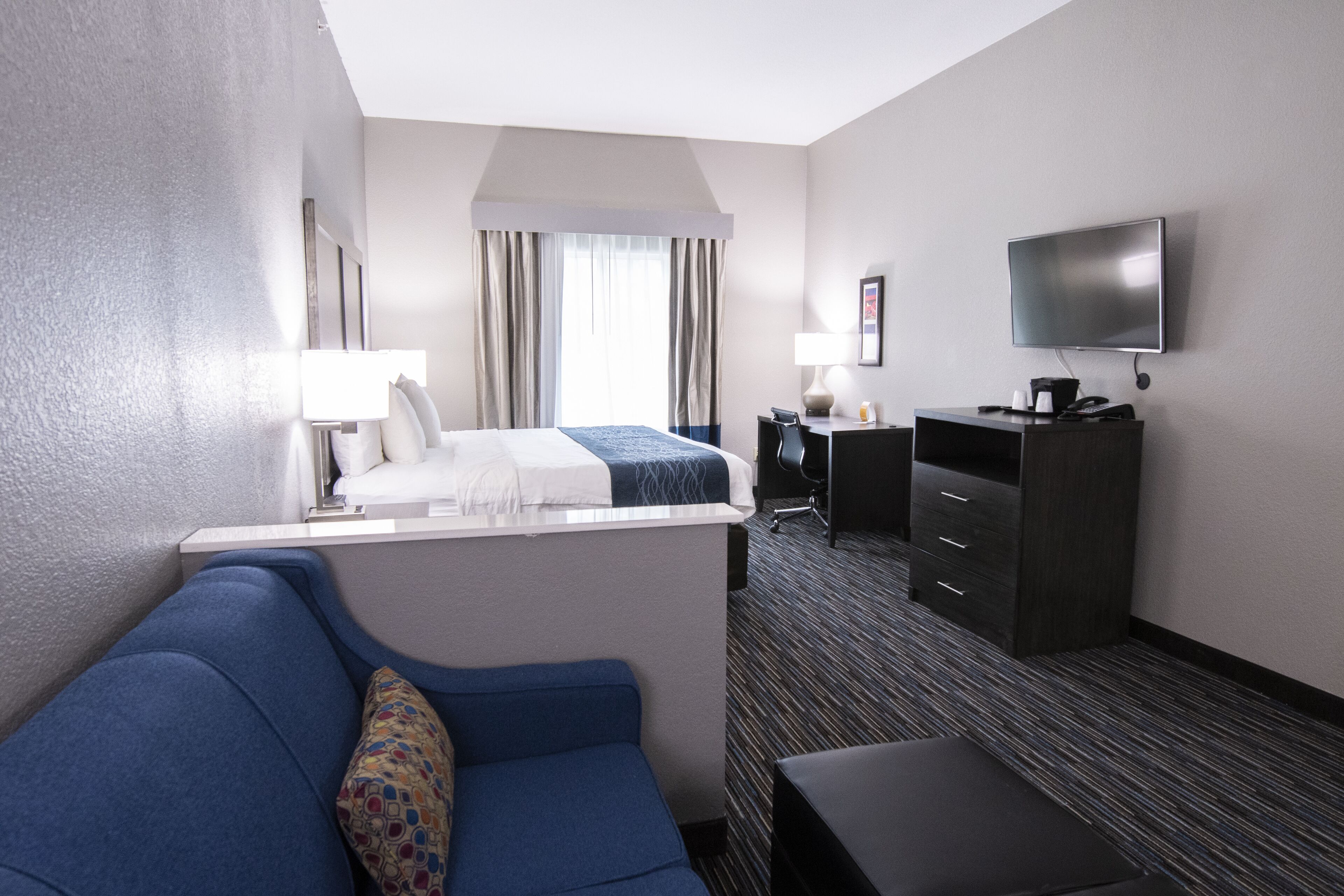 Een hotelkamer met een bed, een bureau, een televisie en een bank.